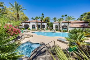 Las Vegas apartment for rent - A pool surrounded by palm trees and apartments in the background.
