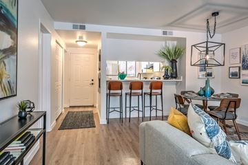 Boise apartment for rent - A living room with a grey couch and a bar area with stools.
