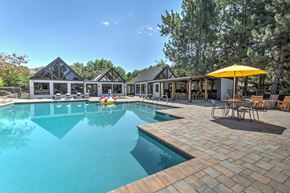 Boise apartment for rent - A large outdoor swimming pool with a yellow umbrella and a house in the background.