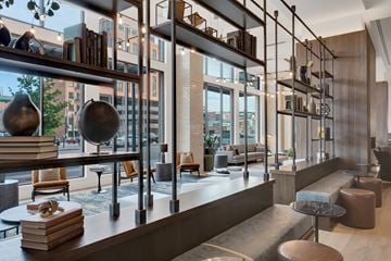 Denver apartment for rent - A modern living room with a long bookshelf and a view of the city.