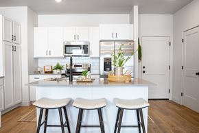 Lehi townhouse for rent - a kitchen with white cabinets and a large island with three stools