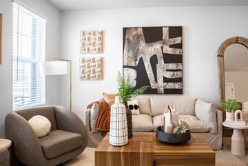 Lehi townhouse for rent - A living room with a grey armchair, a wooden coffee table, a large abstract painting on the wall, and a mirror on the right side.