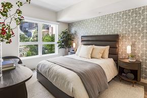 Burbank apartment for rent - A bedroom with a large bed and a window overlooking a garden.