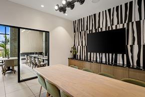 Burbank apartment for rent - A conference room with a long table and chairs, a television on the wall, and a glass wall leading to an outdoor dining area.