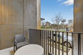 Portland apartment for rent - A chair and table are on a balcony with a view of a parking lot and buildings.