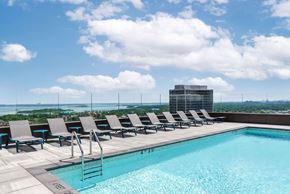 New Rochelle apartment for rent - A pool with chairs and a building in the background.