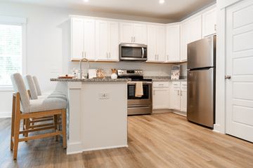 Leland apartment for rent - A kitchen with white cabinets and a wooden chair.