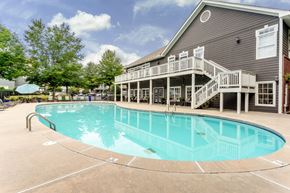 Fairburn apartment for rent - A large outdoor swimming pool with a deck and stairs leading to a building.