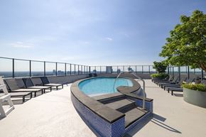 Vienna apartment for rent - A pool on a rooftop with lounge chairs and a fence.