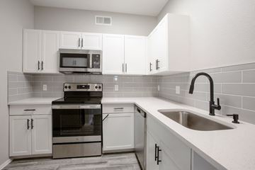 Phoenix apartment for rent - A kitchen with white cabinets and a black stove top oven.