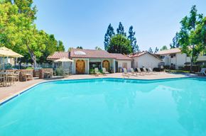La Mesa apartment for rent - A large swimming pool in front of a house with a patio and trees in the background.