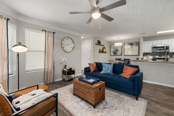 Cary apartment for rent - A living room with a blue couch and a ceiling fan.