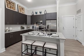 Apex apartment for rent - A kitchen with a a white counter, black cabinets, and three barstools