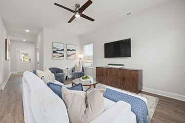Knightdale apartment for rent - A living room with a white couch and a ceiling fan.
