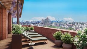 New York apartment for rent - A balcony with a chair and a table with a view of a city skyline.