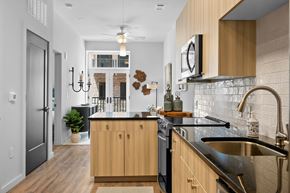 Simpsonville apartment for rent - A kitchen with wood cabinets and white subway tile backsplash, with a French doors overlooking a balcony at Avvio & Prossimo apartments in Simpsonville, SC.