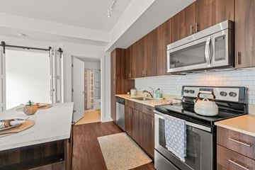 Bothell apartment for rent - A modern kitchen with dark wood cabinets and a black stove top.