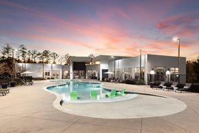 Sandy Springs apartment for rent - A modern building with a pool in the foreground and a beautiful sunset in the background.