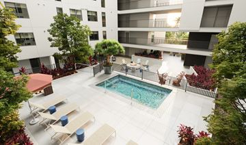 Los Angeles apartment for rent - A pool surrounded by lounge chairs and trees.