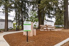 Vancouver apartment for rent - a sign and logs in a yard in front of trees at The Farmstead, Washington, 98684