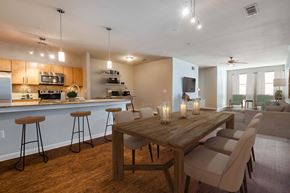 Houston apartment for rent - A modern kitchen with a bar area and a dining table with chairs.