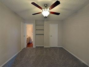 Houston apartment for rent - Model home bedroom with built in shelving, bathroom access, and door