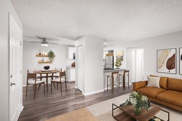Littleton apartment for rent - A living room with a brown couch and a dining table with chairs.