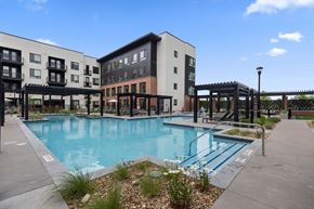 Denver apartment for rent - A swimming pool in front of a building with a black fence.