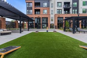 Denver apartment for rent - A grassy area in front of a building with a black pergola.