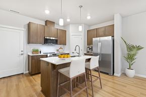 Vancouver apartment for rent - a kitchen with wooden cabinets and a white island with three stools