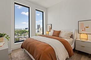 Raleigh apartment for rent - A bedroom with a large bed and a view of the city.