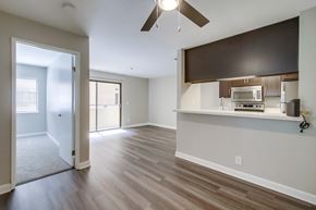 San Diego apartment for rent - A spacious living room with a ceiling fan and a kitchenette in the background.