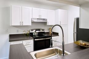 Morgan Hill apartment for rent - A modern kitchen with white cabinets and a black stove top.