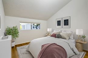 Ontario apartment for rent - A bedroom with a bed, two lamps, and a potted plant.