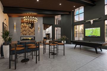 Davie apartment for rent - A modern living room with a pool table and a television displaying a sports game.