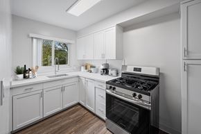 San Mateo apartment for rent - A modern kitchen with white cabinets and a stainless steel stove. at Hillsdale Garden, San Mateo, 94403