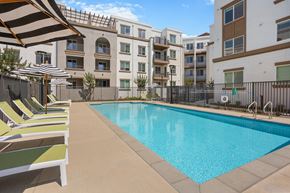 Fontana apartment for rent - A swimming pool surrounded by sun loungers and apartment buildings.
