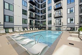 Raleigh apartment for rent - A large outdoor swimming pool with lounge chairs is surrounded by apartment buildings.