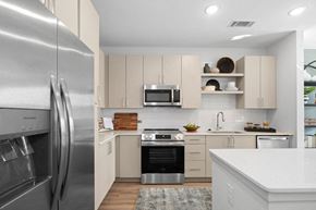 Raleigh apartment for rent - A modern kitchen with a stainless steel refrigerator and white countertops.