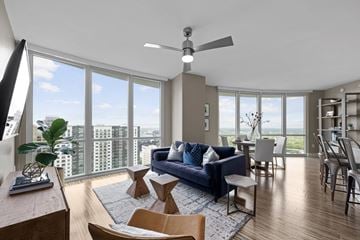 Charlotte apartment for rent - a living room with a blue couch and a dining room table with a large window