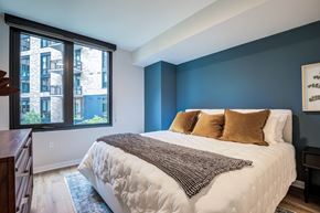 Arlington apartment for rent - A bedroom with a large bed and a window overlooking a building.