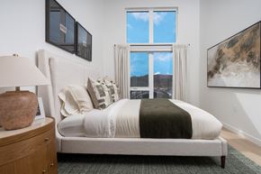 Woodinville apartment for rent - A bedroom with a large bed and a view of the city through the window.