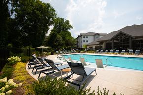 Raleigh apartment for rent - A pool with chairs around it and trees in the background.