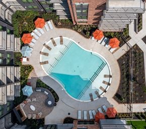 Nashville apartment for rent - An aerial view of a swimming pool surrounded by orange umbrellas and concrete structures.