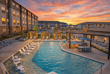 Denton apartment for rent - A large outdoor swimming pool surrounded by lounge chairs and umbrellas.