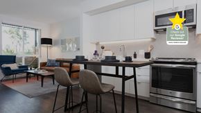 Oakland apartment for rent - A modern kitchen with white cabinets and a large island with chairs around it.