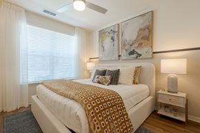 Land O'lakes apartment for rent - A bedroom with a bed, nightstand, and two wall art pieces.