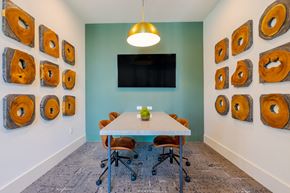 Land O'lakes apartment for rent - A conference room with a white table and chairs, a television, and a wall of wood slices.
