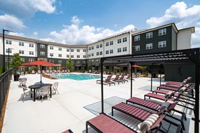 Fairburn apartment for rent - A pool area with a table and chairs and a building in the background.