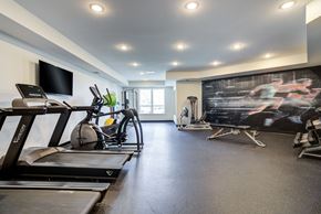 Shakopee apartment for rent - a gym with treadmills and weights and a tv on the wall